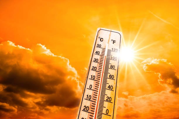 Hot summer or heat wave background, glowing sun on orange sky with thermometer
